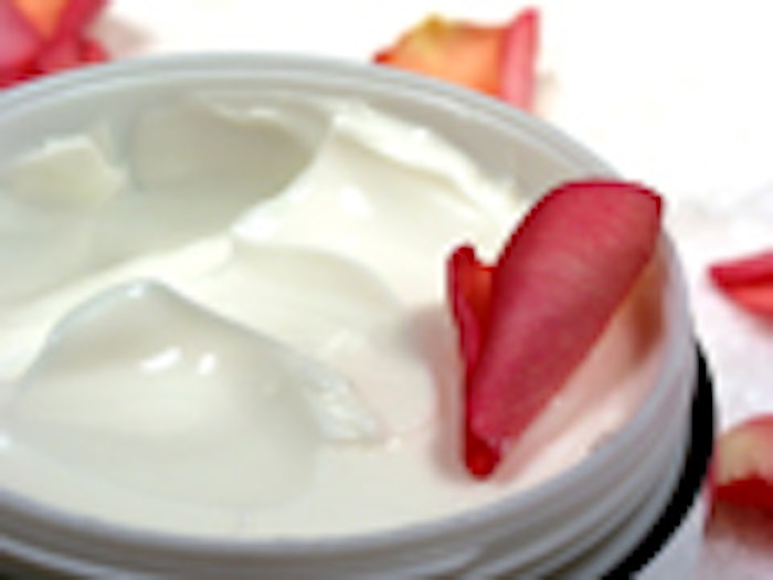 Body cream with rose petals on white towel, closeup
