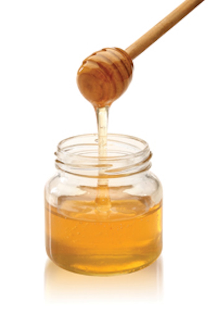 Honey With Wood Stick Pouring
