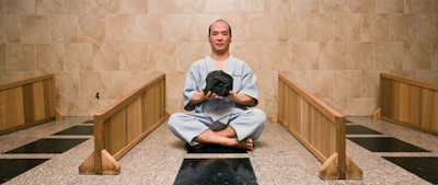 Co-owner of Iyashi Bedrock Spa, Ryusuke Juge, wields a sample of the black silica rock used in his spa’s stone beds.