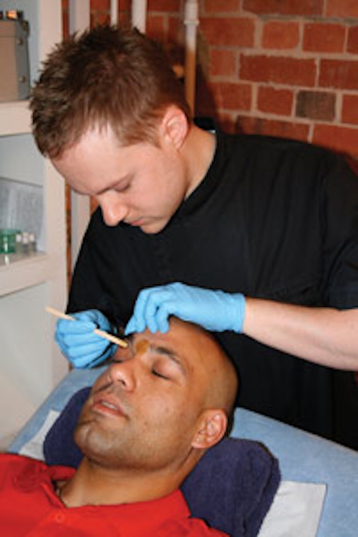Author Andy Rouillard performs an eyebrow wax on a male client.