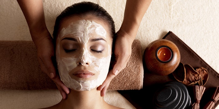 Spa massage for young woman with facial mask on face - indoors