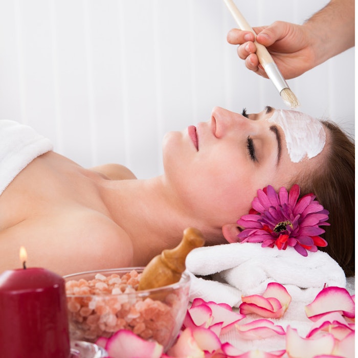 Woman getting facial mask at spa studio