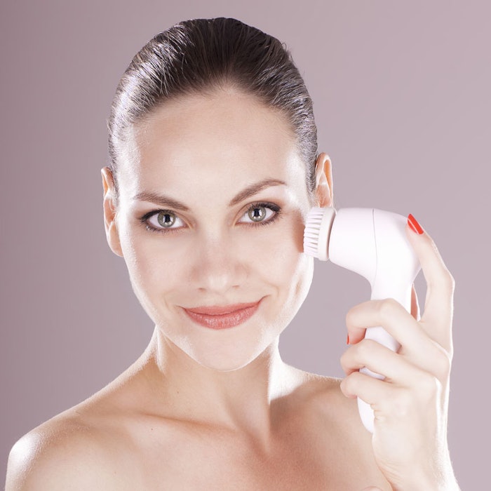 Charming woman with brush for deep cleansing facial. Skin care c