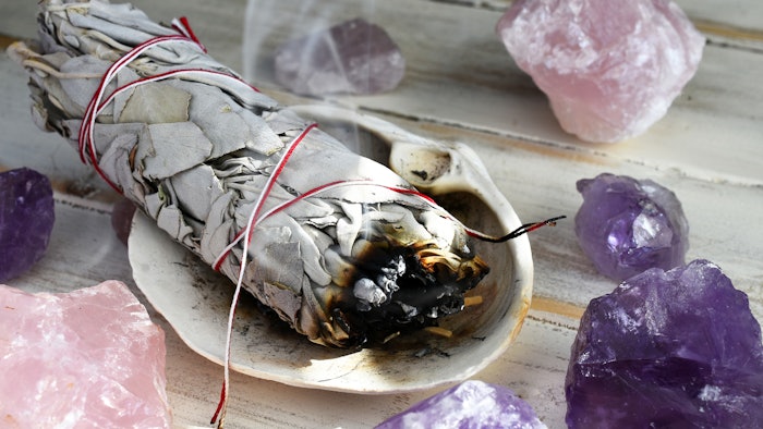 Burning sage smudge stick with crystals