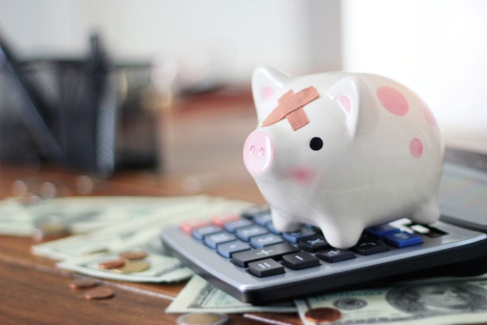 Finance concept: a piggy bank with a band-aid, sitting on a calculator