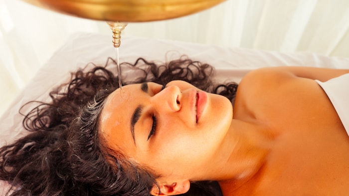 Woman getting shirodhara treatment