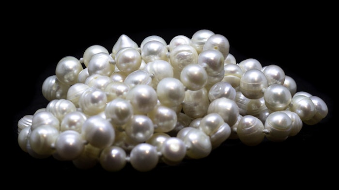 Thread of natural white baroque pearl beads on black background