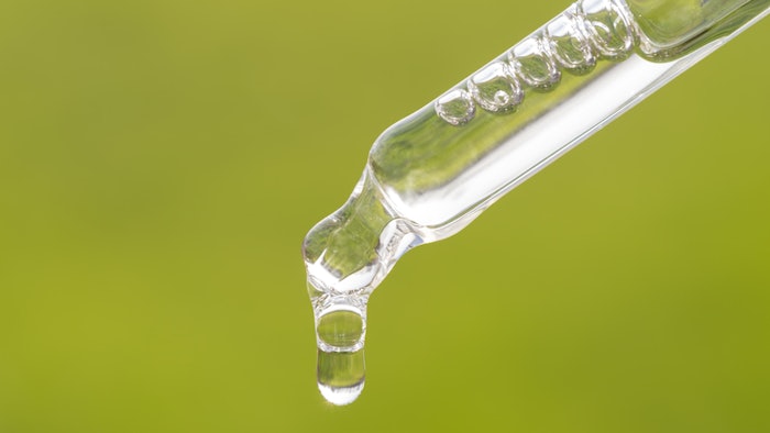 Pipette with CBD oil, tincture on grass background. Alternative medicine with green