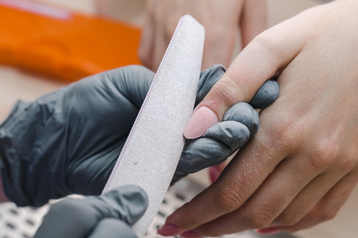 Manicurist shaping the nail