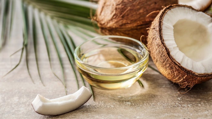 Bowl with coconut oil on table next to whole coconuts