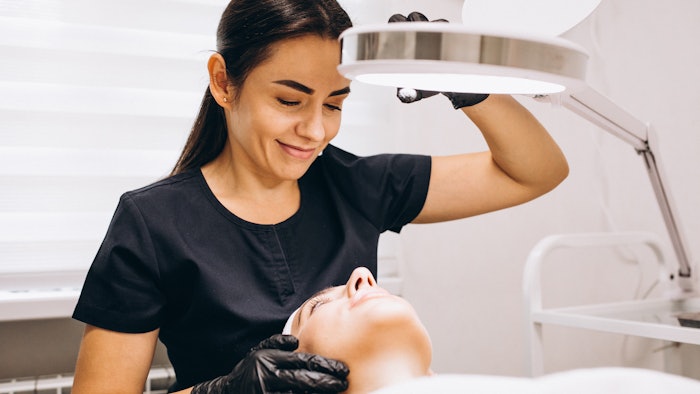Esthetician inspecting client's skin