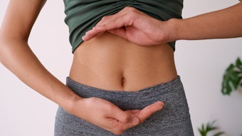 Close up of a young multi-ethnic woman's stomach cupped by her hands, gut health