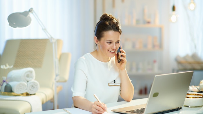 woman attendant working at spa beauty salon answering phone