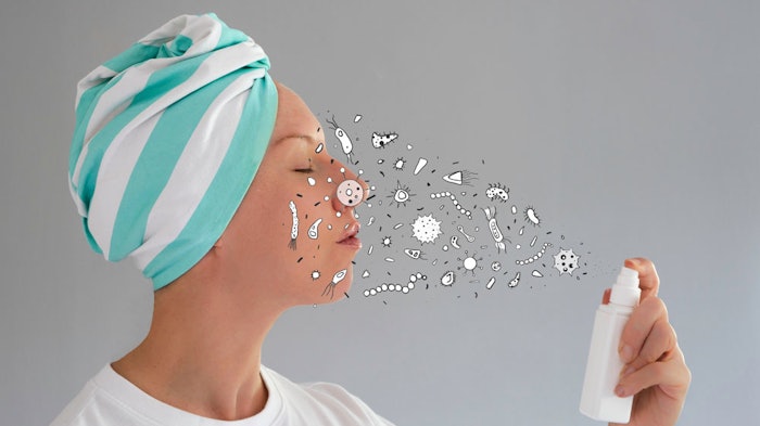 Woman spraying face with toner