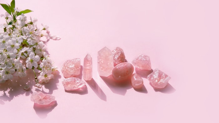 set of rose quartz minerals and spring white flowers on pink abstract background. Gemstones for Healing Crystal Ritual. esoteric spiritual practice for aura cleansing, relax, harmony