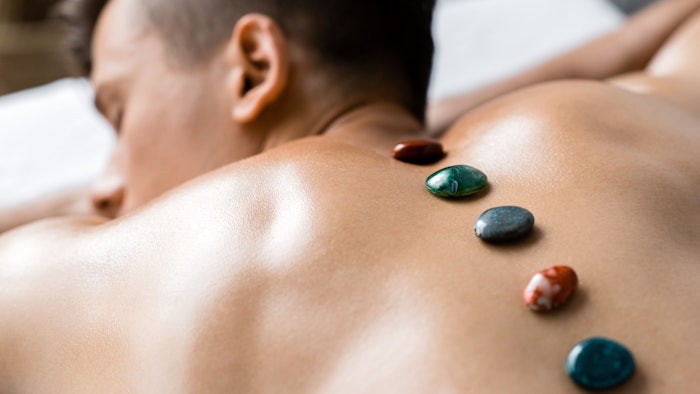 selective focus of shirtless man with colorful stones on his back