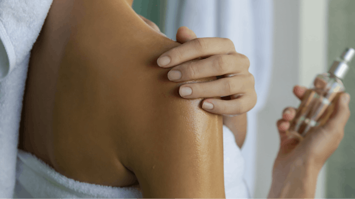 Woman applying body oil to moisturize her skin after shower, beauty skin care concept
