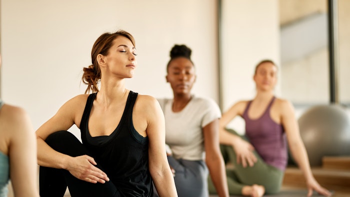 Group of athletic women doing stretching exercises at health club.