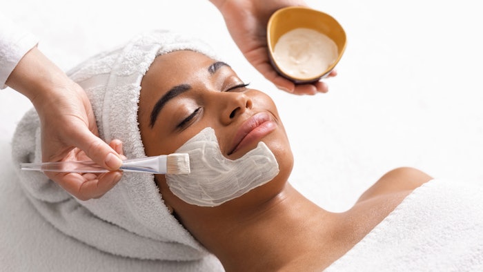 Top view of beauty therapist applying face mask