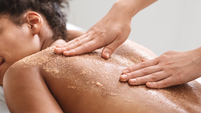 African american lady having skin scrubbing procedure at spa salon