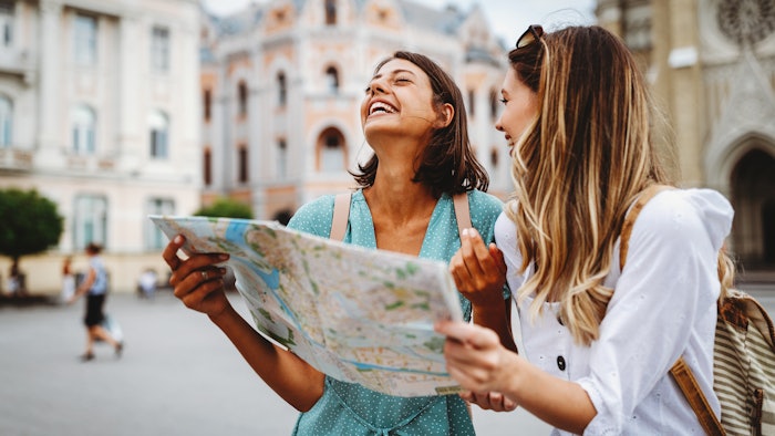 Fun, friends, travel and tourism concept. Beautiful girls looking for direction in the city