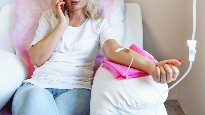 Woman in hospital talking at mobile phone while needle is in arm, Vitamin Therapy Iv Drip Infusion In Women Blood