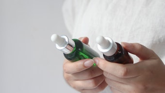 Female hands holding two bottles of facial essential oil or serum packaging. Woman choosing beauty products.