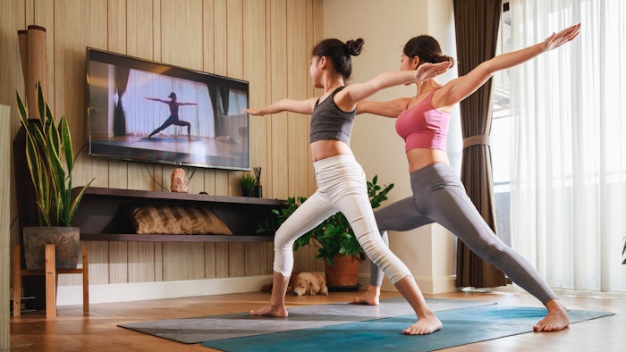 Asian woman and Little girl practicing yoga from yoga online course via smart TV at home. Healthy lifestyle - cozy cardio at home.