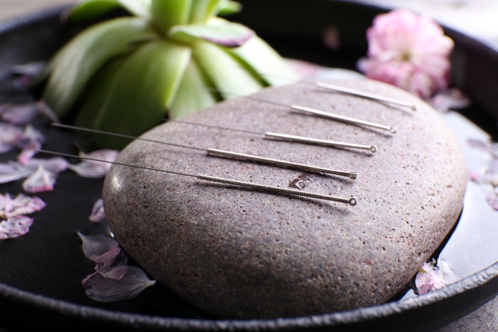 Acupuncture needles with spa stone on tray, closeup