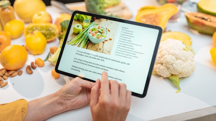 Woman looking on the digital recipe, using touchscreen tablet while cooking healthy meal on the kitchen at home, close-up view on the screen