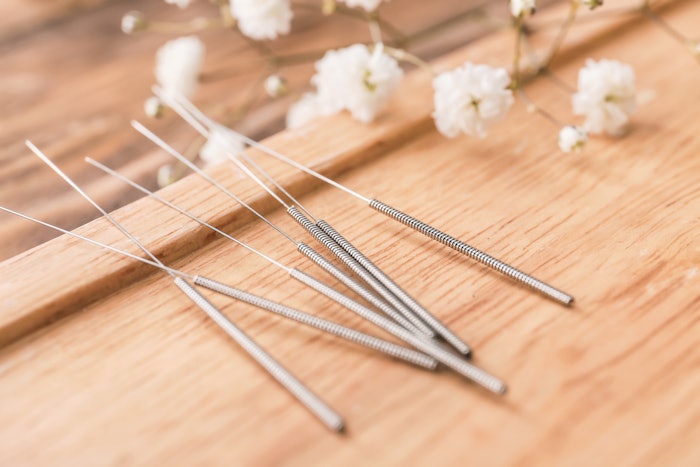 Stand with acupuncture needles on wooden background, closeup