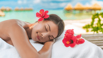 Luxury hotel spa massage table Asian woman relaxing on exotic travel vacation on beach. Summer pampering lifestyle skincare body care.