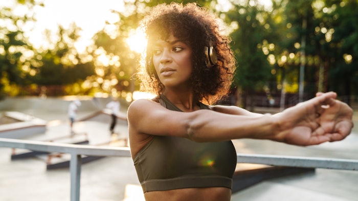 Image of african american sportswoman doing exercise on sports ground
