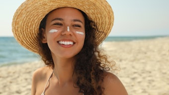 Beautiful African American woman with sun protection cream on face at beach