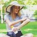 Young woman a bottle of sunblock outside on a summer day