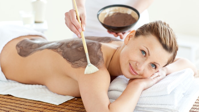 Delighted caucasian woman receiving a beauty treatment with mud