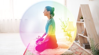 mindfulness, spirituality and healthy lifestyle concept - woman meditating in lotus pose at yoga studio over rainbow aura