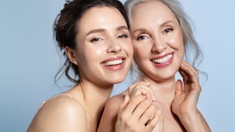 Happy smiling grey-haired senior mother and young daughter holding hand and hugging with love