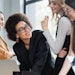 african american businesswoman smiling near multiethnic colleagues near laptop in office