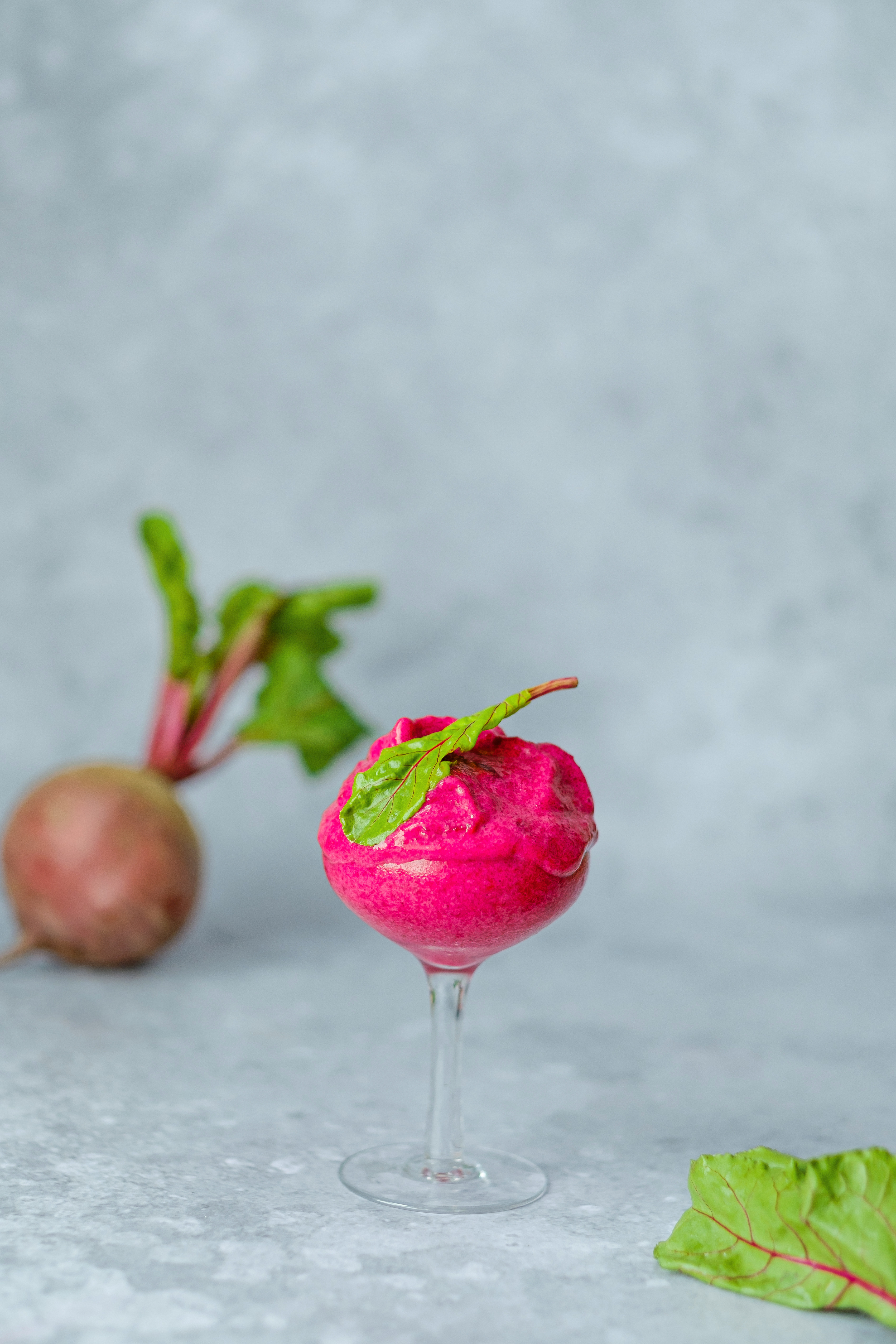 Magenta vegan ice cream with frozen beetroot, banana, avocado and coconut milk in glass on a gray background. A healthy cold vegan dessert.