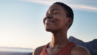 Fitness, calm and breathing of black woman outdoor in nature, mountains and blue sky background for yoga wellness, meditation and zen energy. Face of girl breathing for peace, freedom and mindfulness