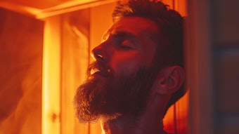 Bearded man relaxing on wooden bench in infrared sauna. Spa treatment