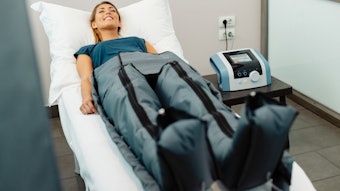 Relaxed woman enjoying lymphatic drainage pressotherapy treatment at wellness center. By Drazen