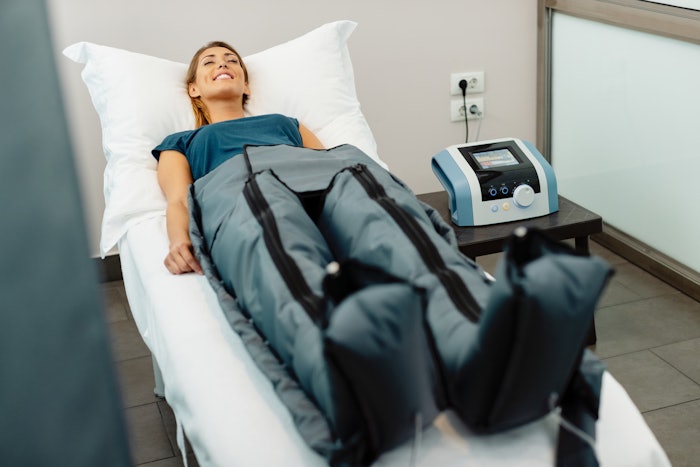 Relaxed woman enjoying lymphatic drainage pressotherapy treatment at wellness center. By Drazen