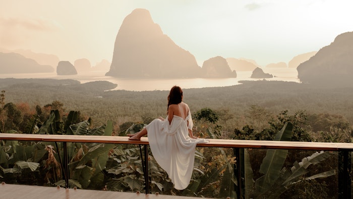 Woman with the white dress sit and see the mountain in early morning at the Sametnangshe Island viewpoint, Phang-Nga, Thailand.