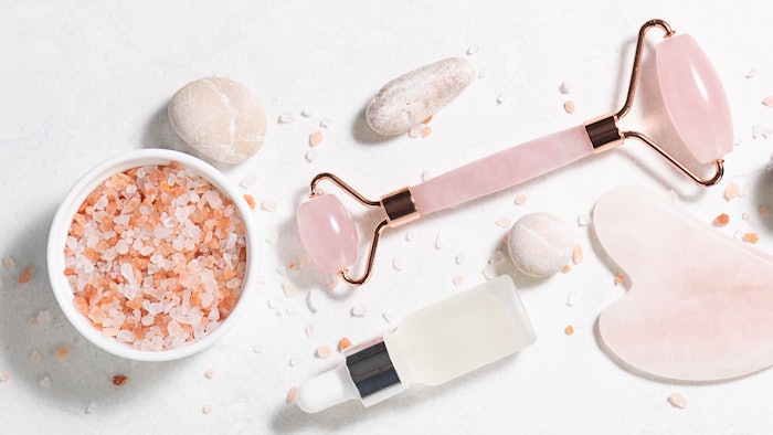 Skin care cosmetic products and Chinese Gua Sha massage tools on white marble background top view. Anti age face care procedures.