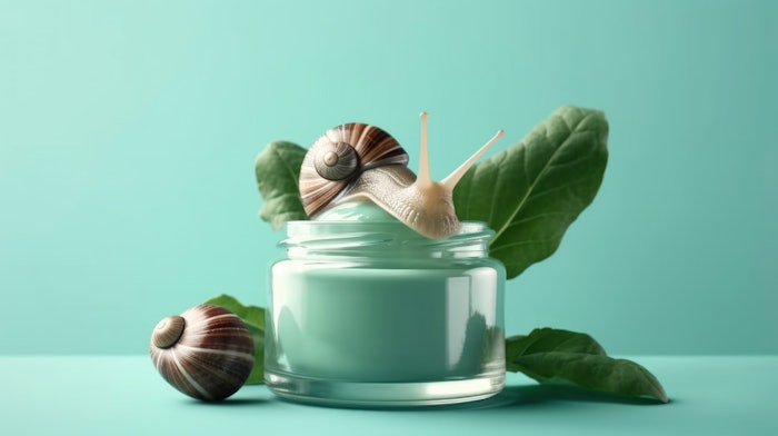 Snail sliding near a jar of face cream
