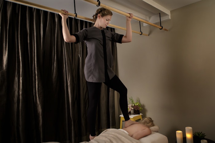 Women standing on back of guest providing deep tissue massage