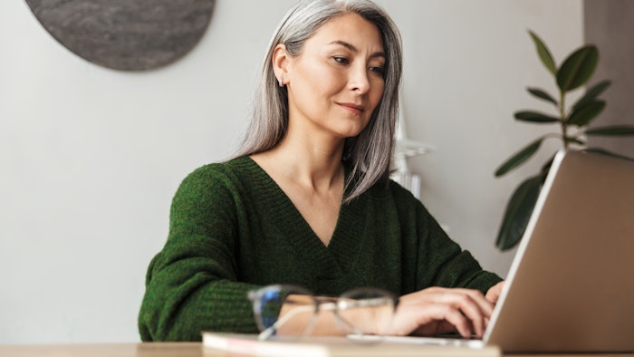 Photo of gray-haired focused businesswoman typing on laptop