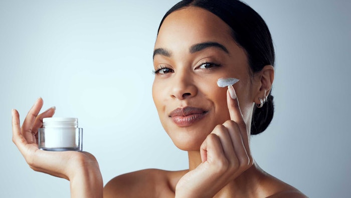 woman smart sassy holding jar of skin cream - hair pulled back - shoulders and up AdobeStock_595997467